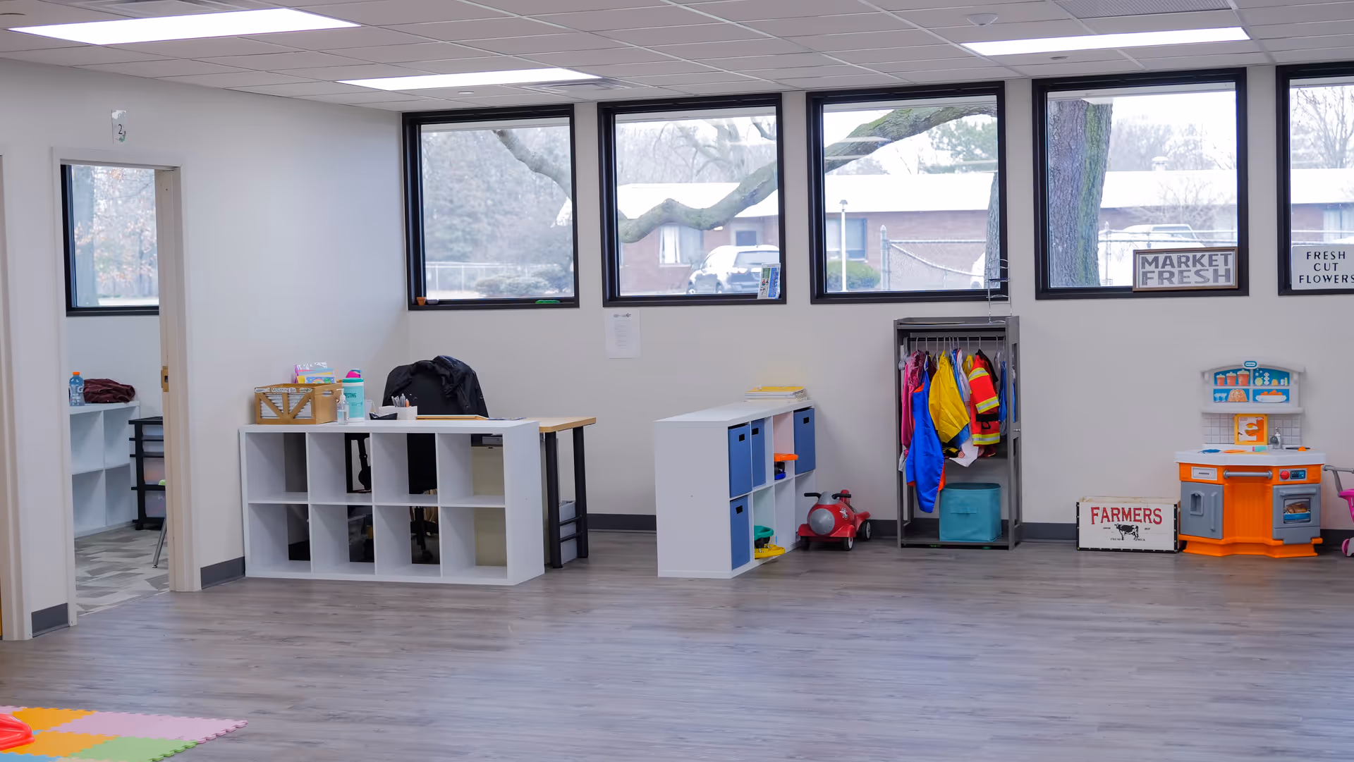 Bright open interior playroom with cubbies, coats, and a toy kitchen.