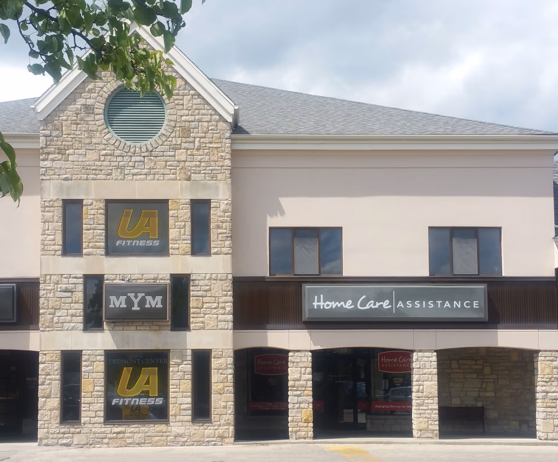 Exterior stone building with Home Care Assistance sign and storefront windows