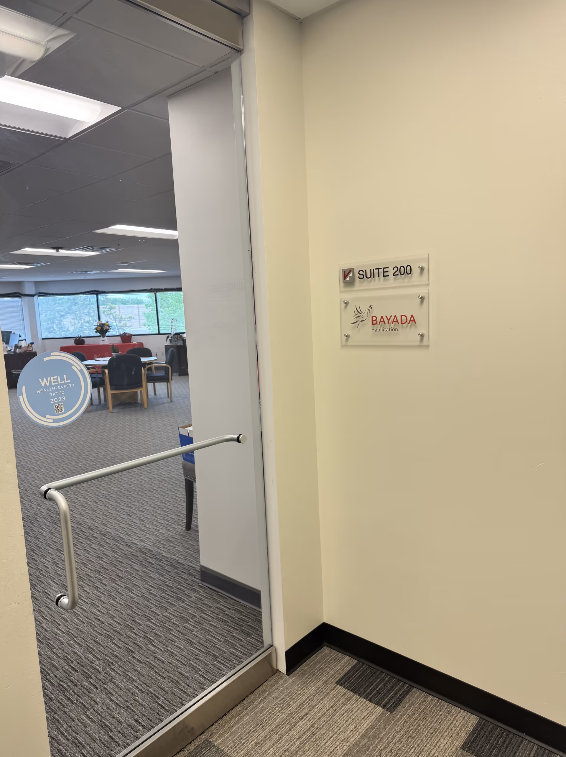 Interior hallway of BAYADA Habilitation showing SUITE 200 sign and a lounge beyond.