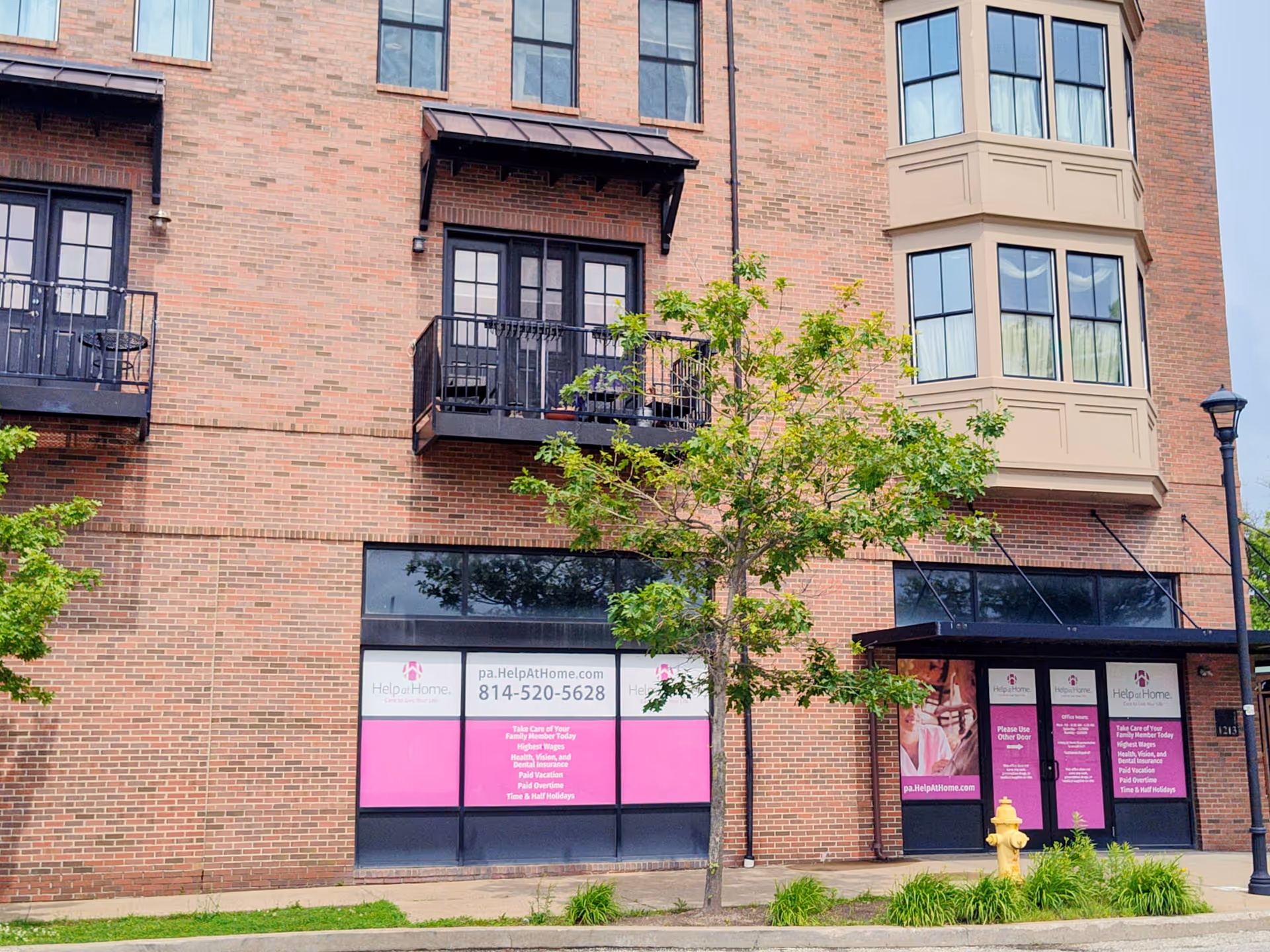 Brick, multi-story building with Help at Home storefront signage on pink panels.