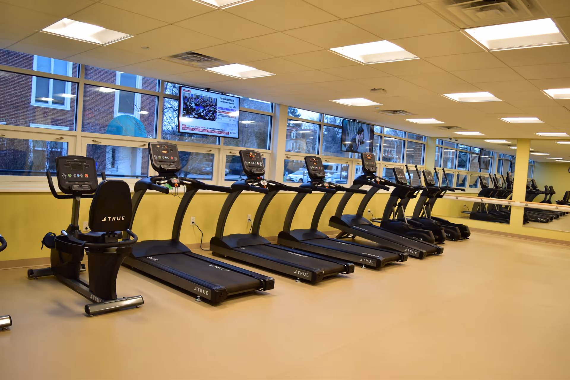 Row of treadmills in a bright indoor fitness room at a senior facility