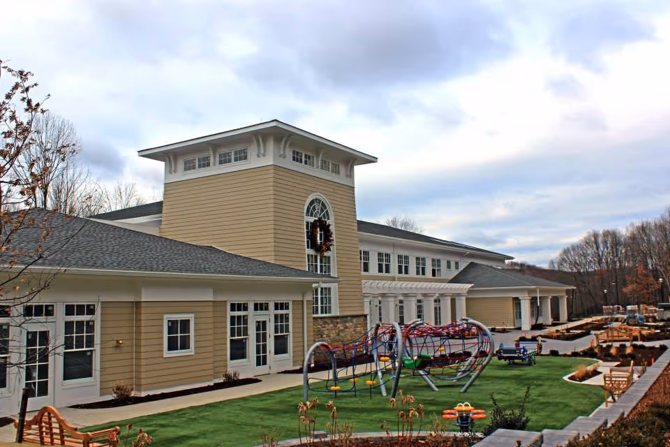 Exterior view of Regional Hospice building with a playground and outdoor seating.