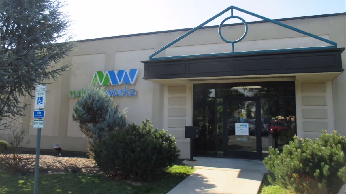 Front view of MobilityWorks building entrance with glass doors and surrounding landscaping.