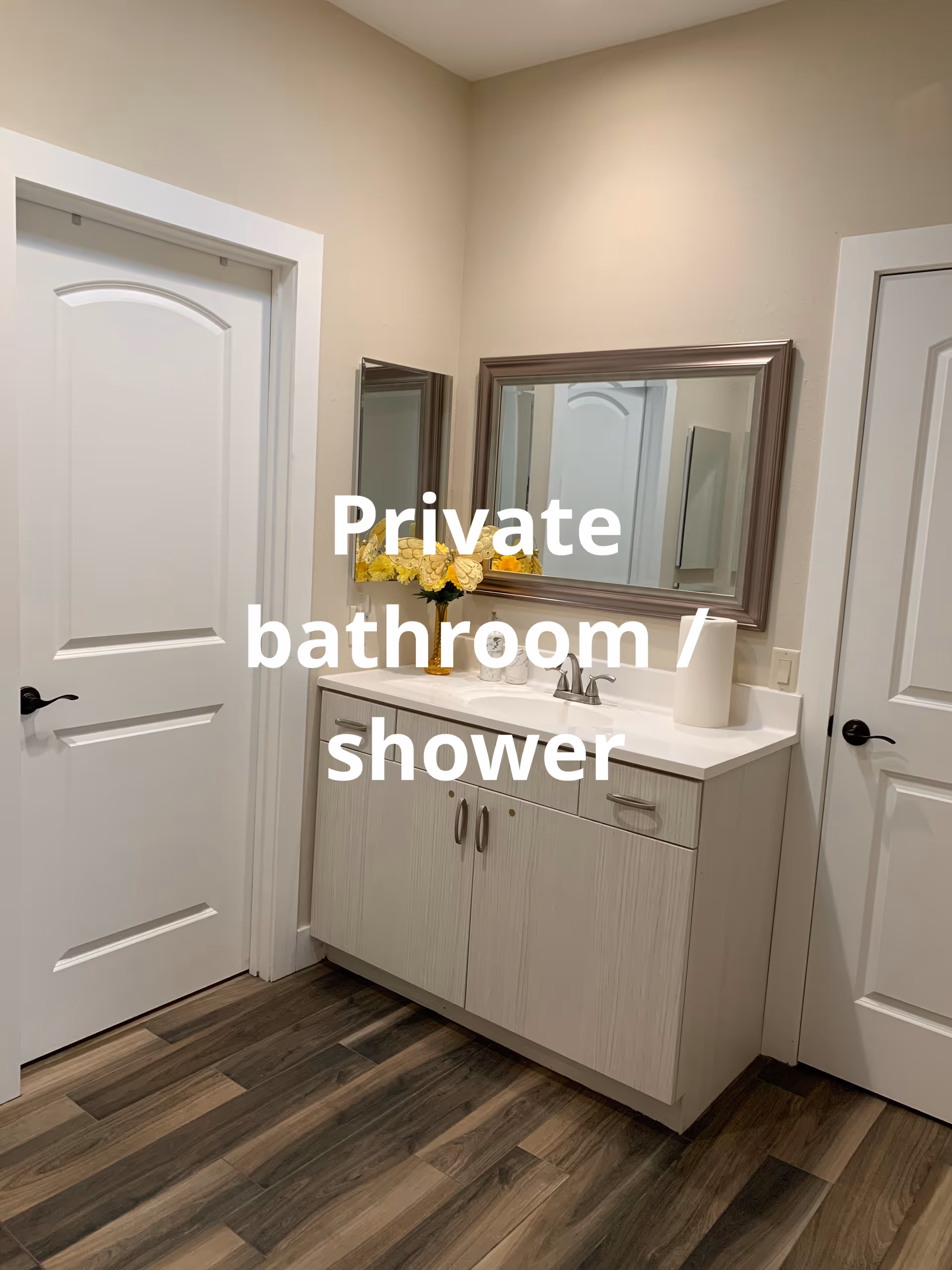 Private bathroom with sink, cabinets, mirror, and yellow flowers on vanity.