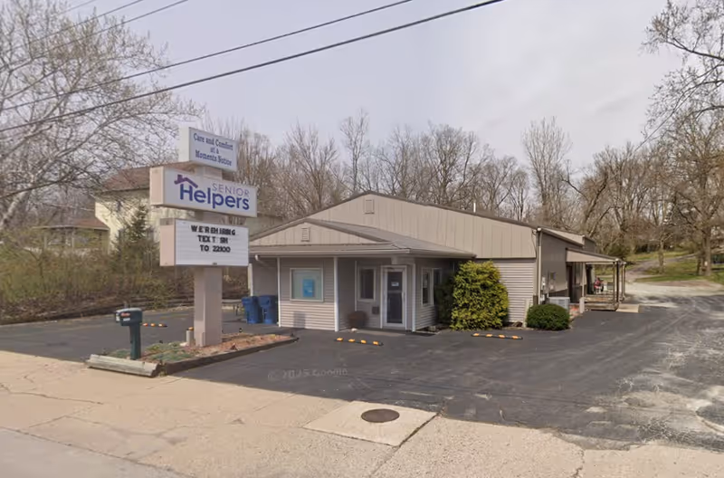 Exterior view of a Senior Helpers facility with a sign and parking area.