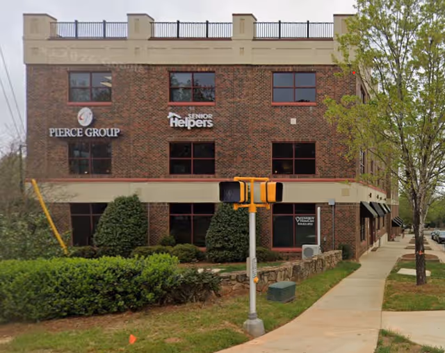 Brick, multi-story senior care building with Senior Helpers sign and landscaped sidewalk in front.
