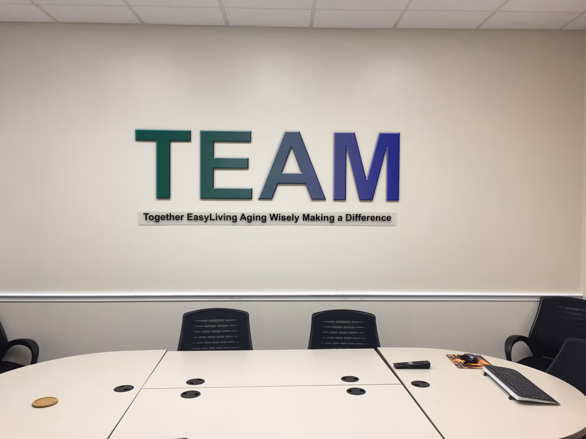 Interior meeting room with large colorful TEAM sign on wall and a round white table.