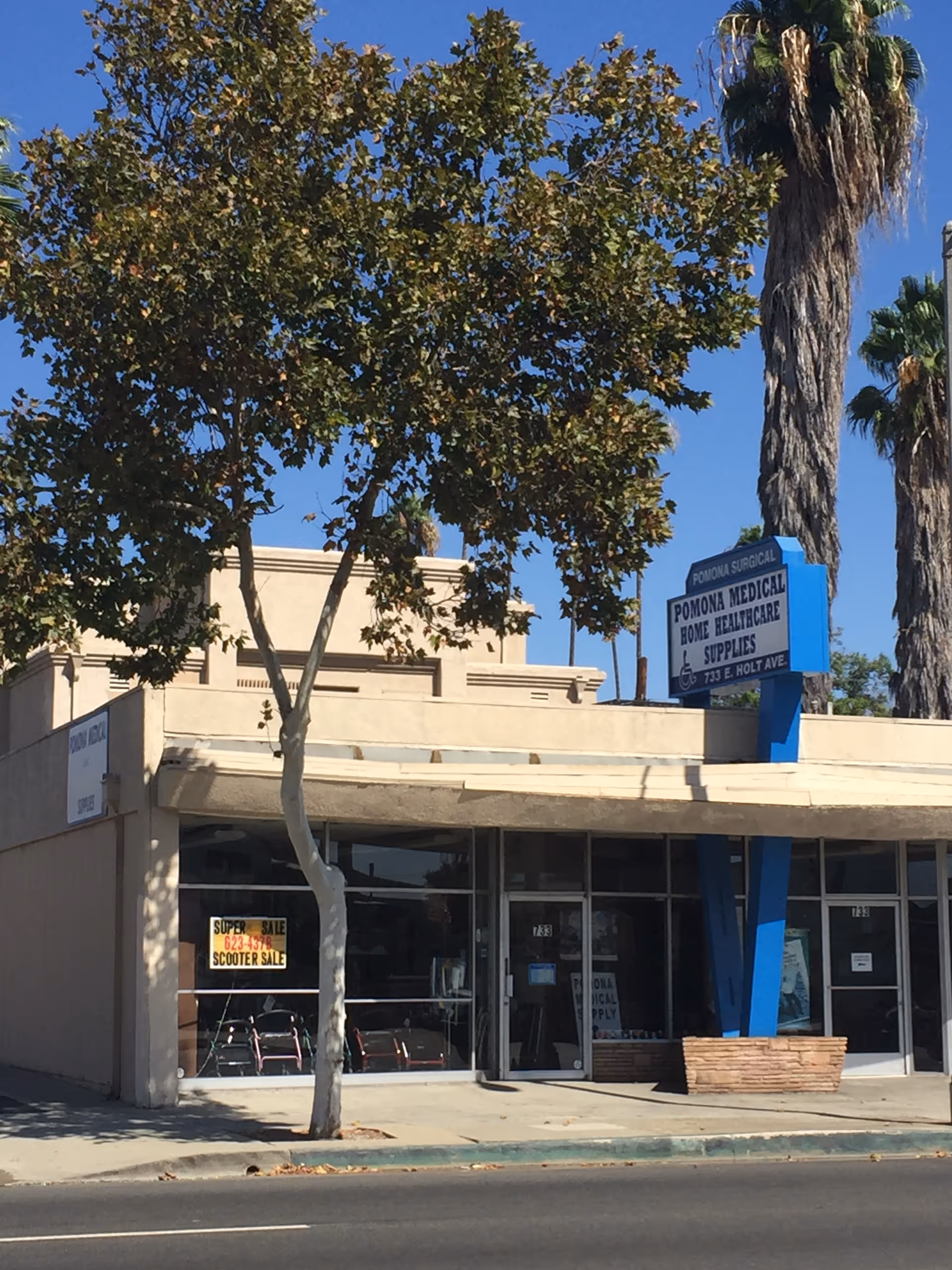 Exterior view of Pomona Medical Supply storefront with large windows and palm trees.