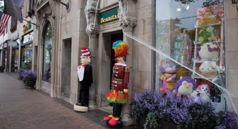 Storefront exterior with holiday nutcracker figures and purple flowers in window display