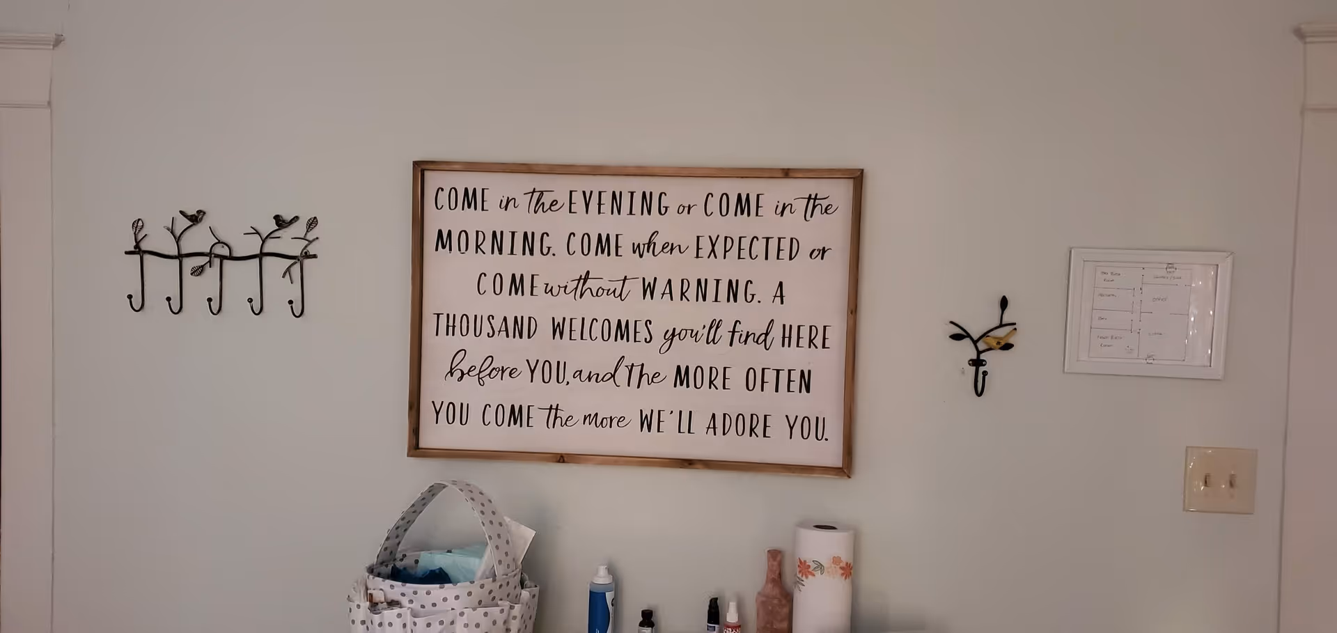 Wall interior with framed inspirational quote, coat hooks, and assorted counter items.