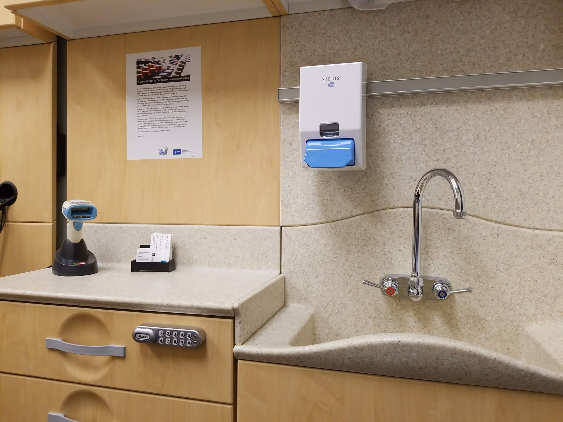 Kitchen area with sink, faucet, sanitizer dispenser, barcode scanner, and cabinets.