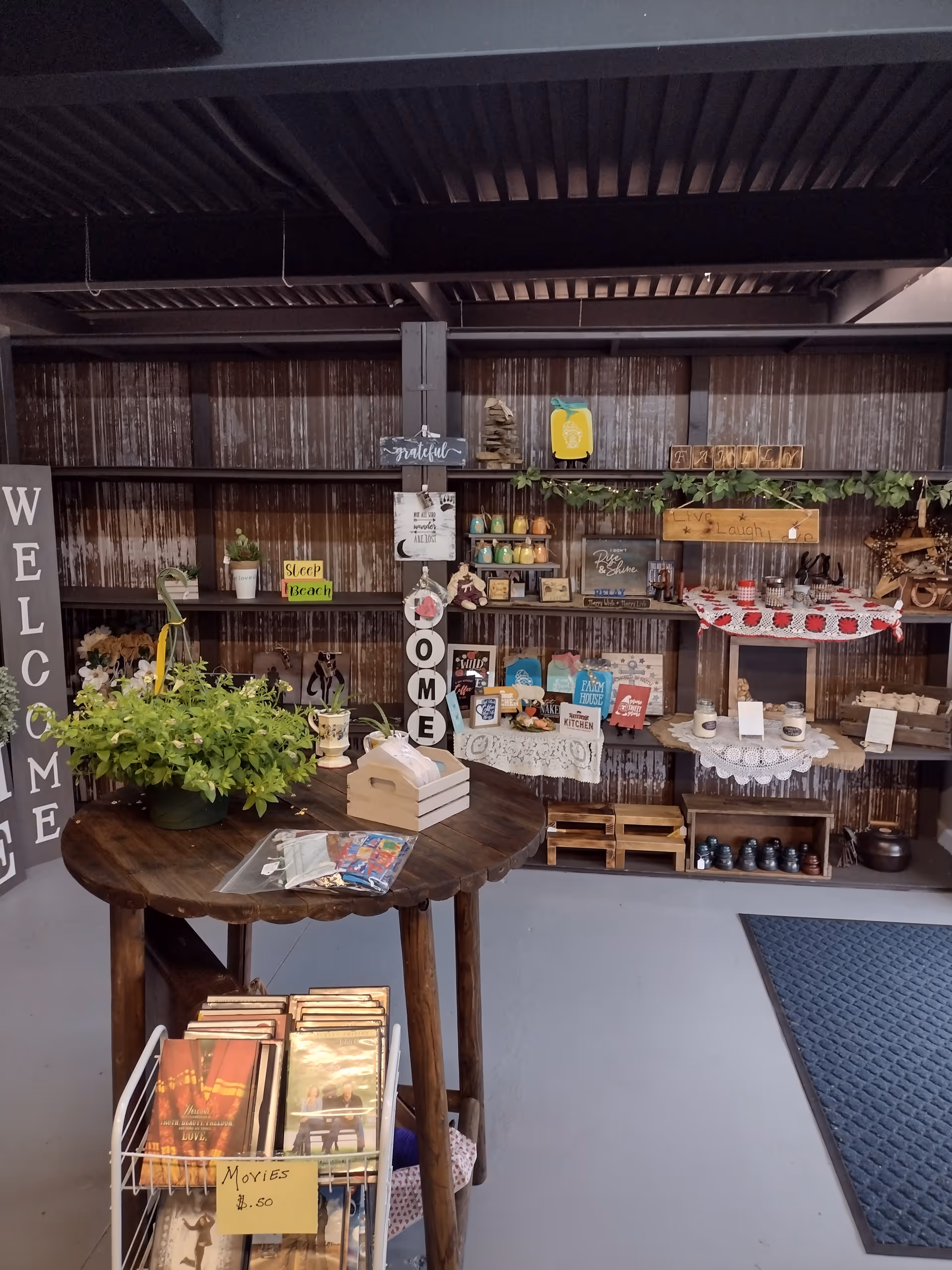 Interior rustic room with round wooden table, potted plant, and shelves of crafts.