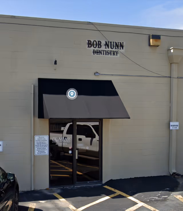 Front exterior of a dentistry office with a glass door and black awning.