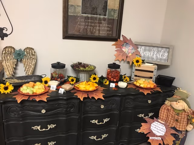 Fall-themed dessert display with sunflowers and pumpkins arranged on a dark ornate sideboard.