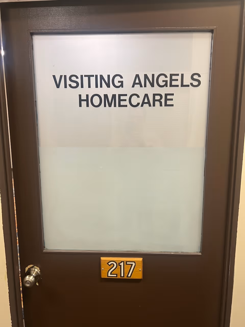 Brown interior door with frosted glass window and Visiting Angels Homecare sign, 217