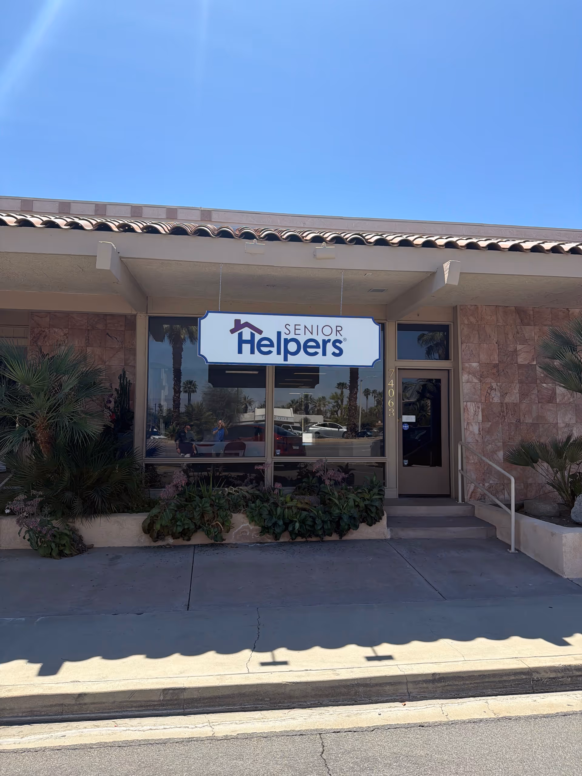 Exterior view of a Senior Helpers storefront with sign and entrance, surrounded by plants.