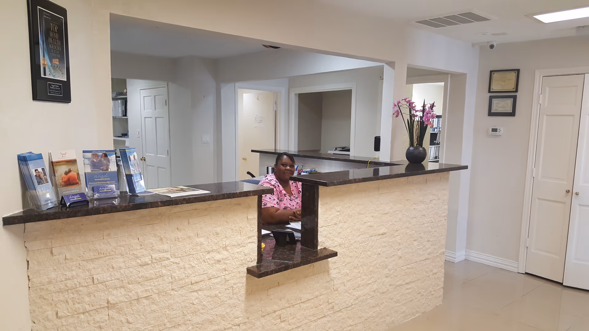 Reception area with a staff member at a dark granite counter inside a senior facility.