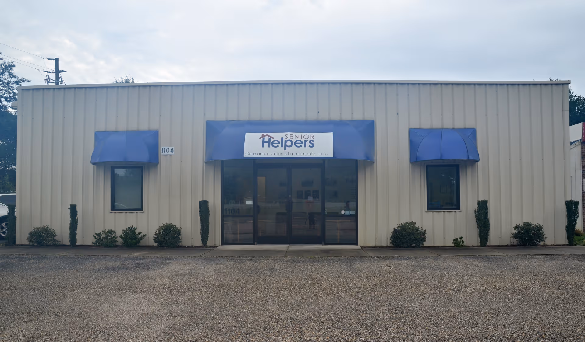 Front view of a Senior Helpers facility with blue awnings and glass doors.