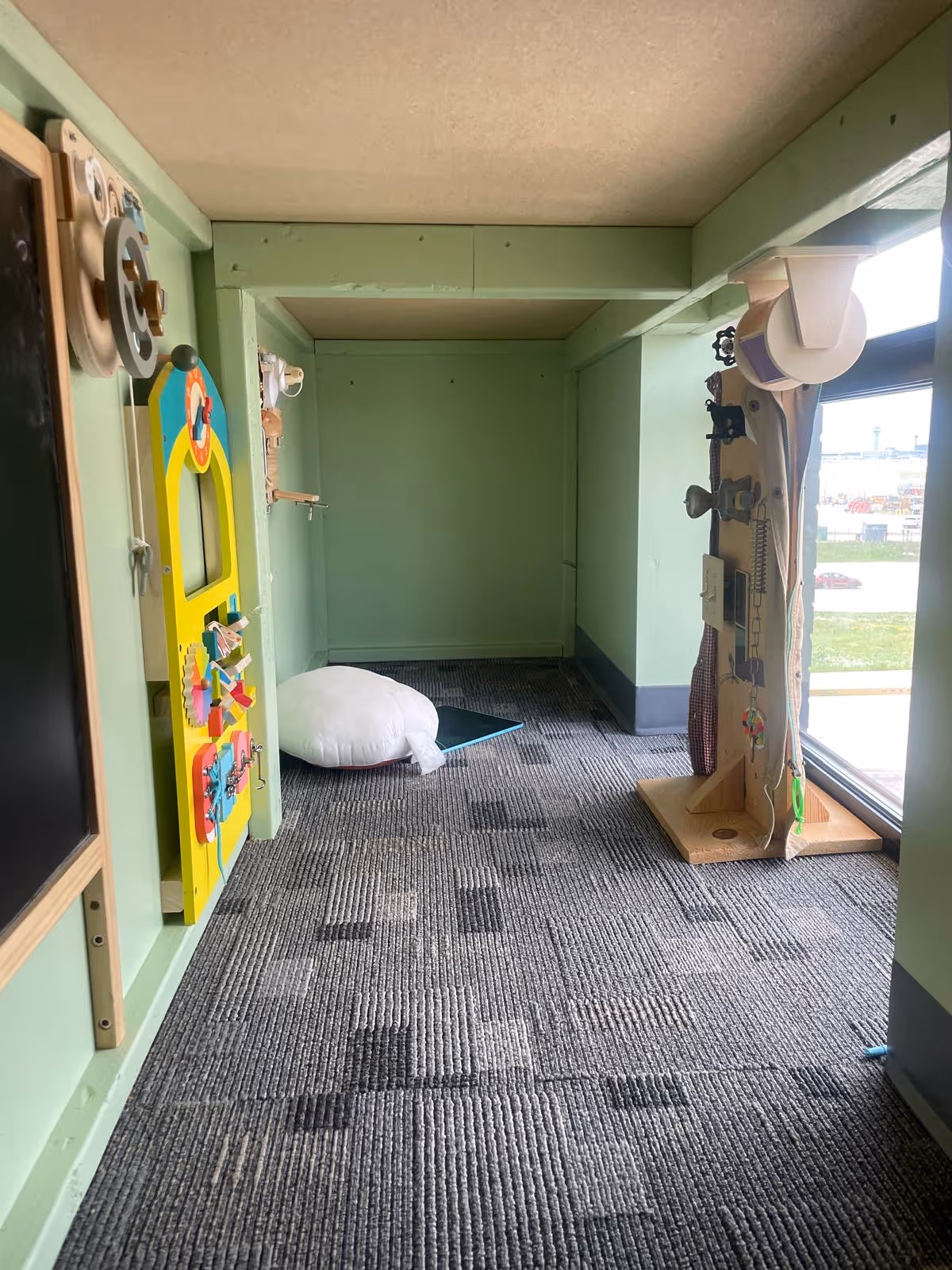 Interior play area in a senior facility with mint walls, toys, and a window view.