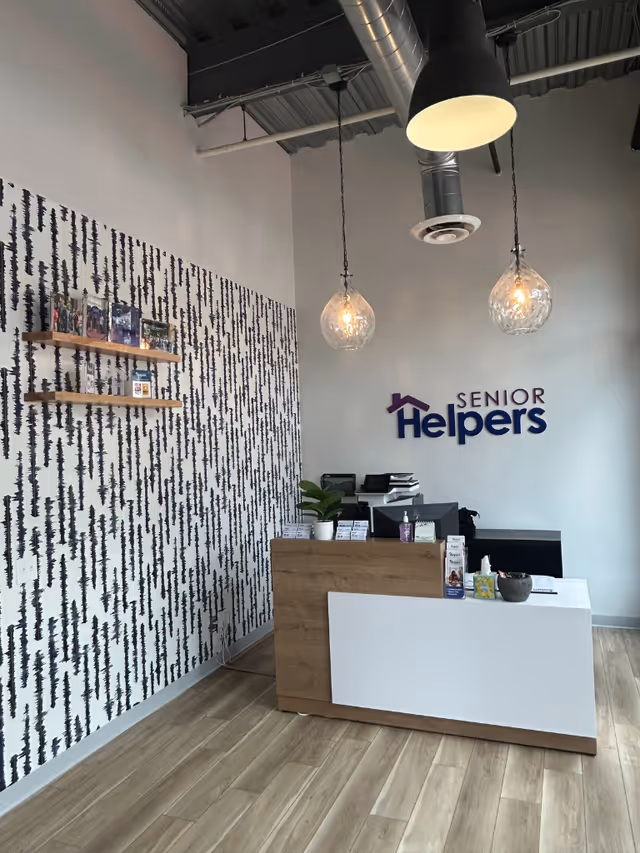 Reception area with Senior Helpers logo, modern decor, pendant lights, and wood floor.