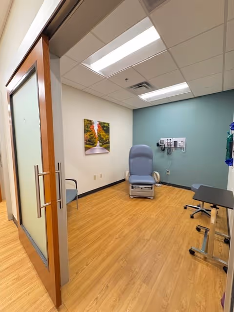 Medical examination room in a senior facility with blue chair and wall-mounted equipment.