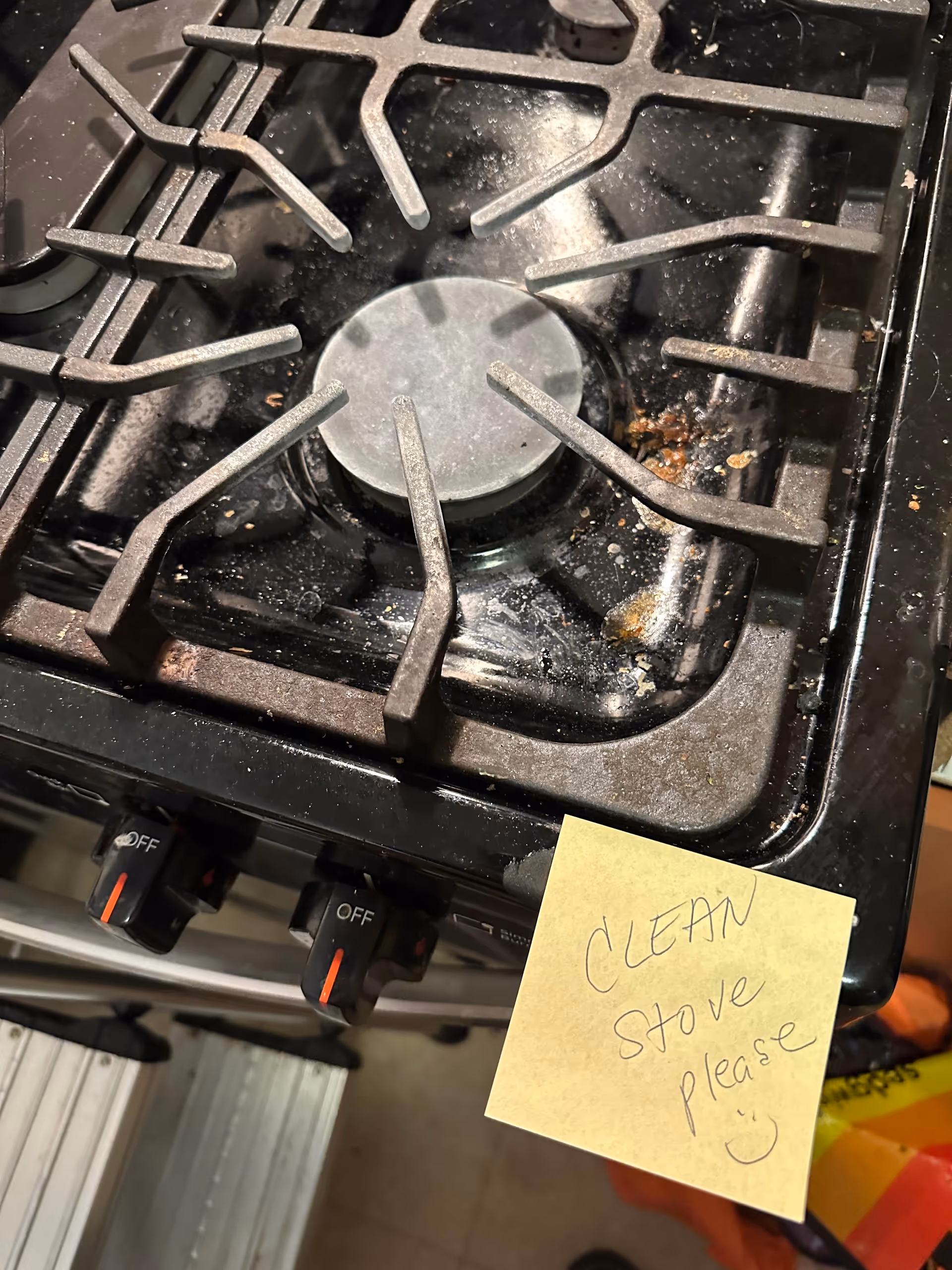 Close-up of a dirty kitchen stove with a 'CLEAN STOVE PLEASE' note.