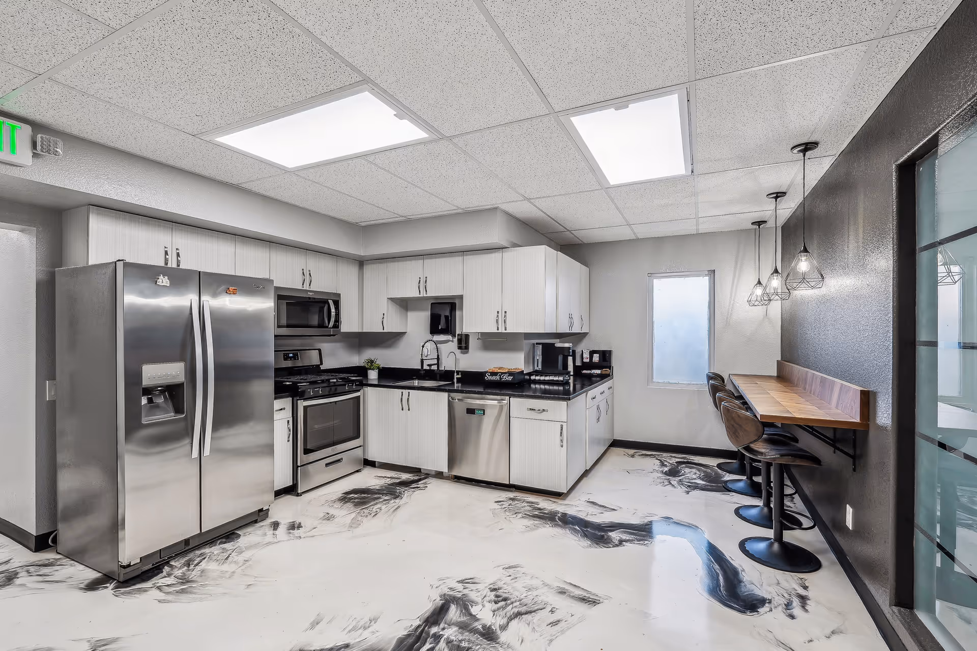Modern stainless steel kitchen in a senior living facility with cabinets and bar seating.