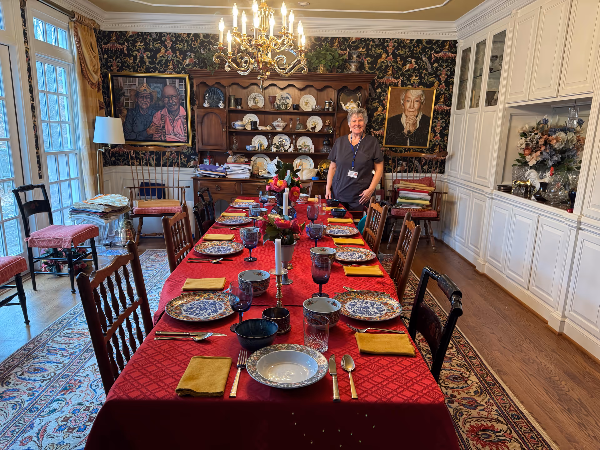 Long dining table set for meals in a traditional dining room with a staff member.