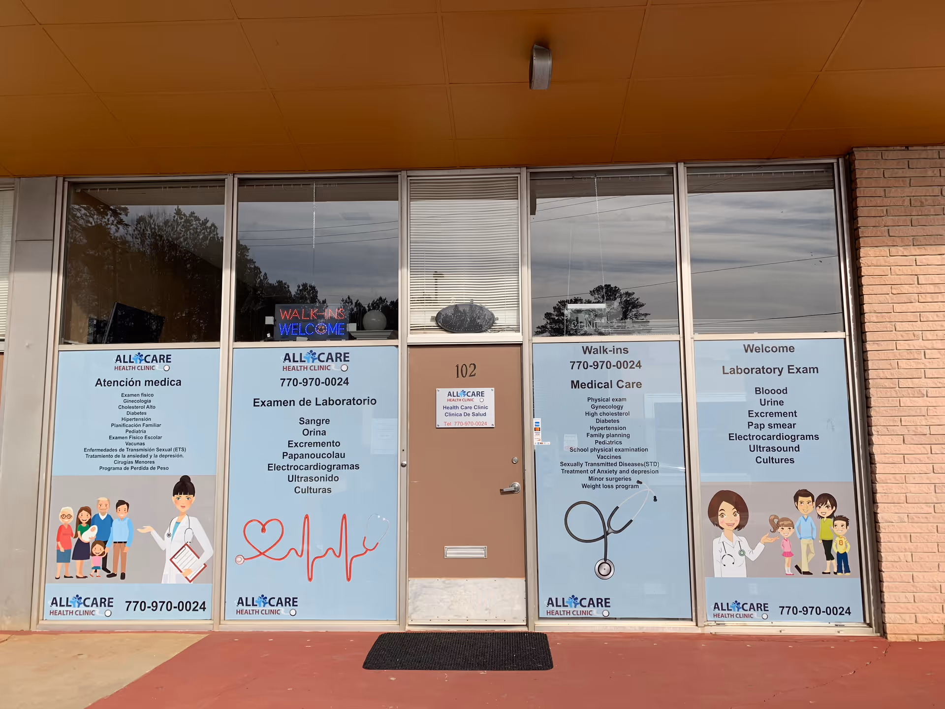 Exterior clinic storefront with glass windows, posters, and a central door labeled 102.