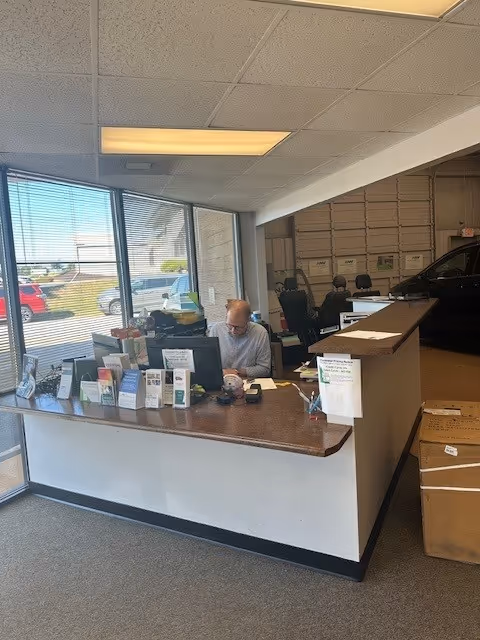 Man sits at a reception desk with brochures in a MobilityWorks showroom.