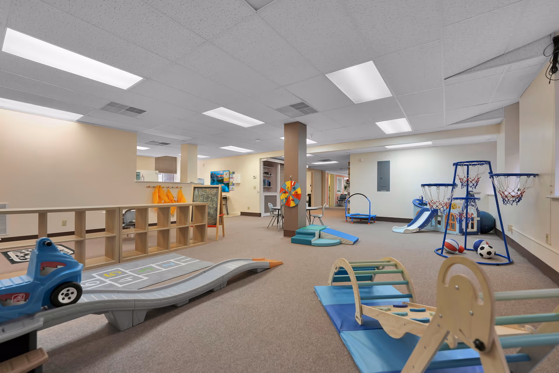 Indoor playroom with ramps, slides, climbing structures, and soft mats for resident activities.