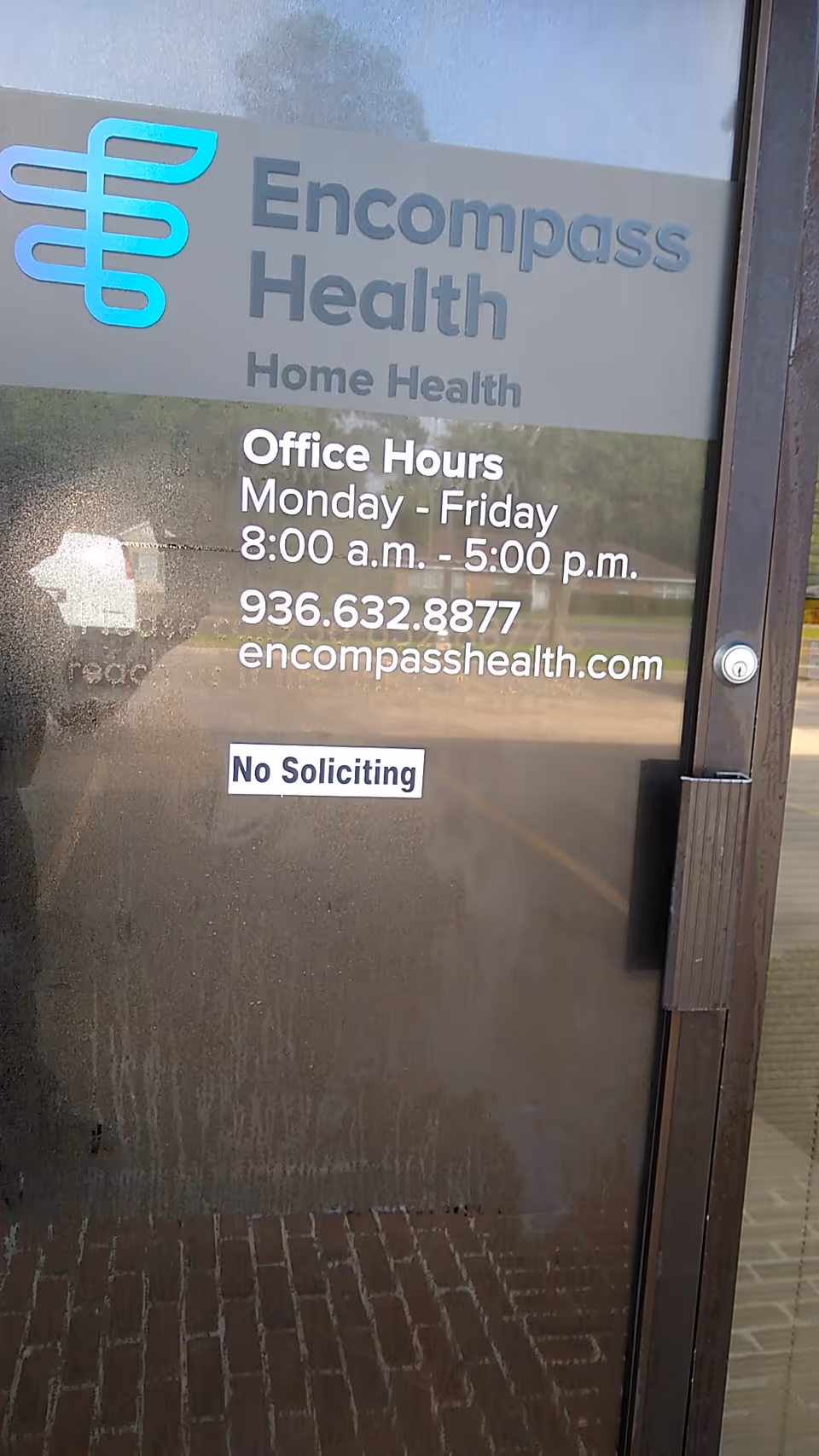 Glass door displays Encompass Health Home Health logo with office hours and contact info, No Soliciting.