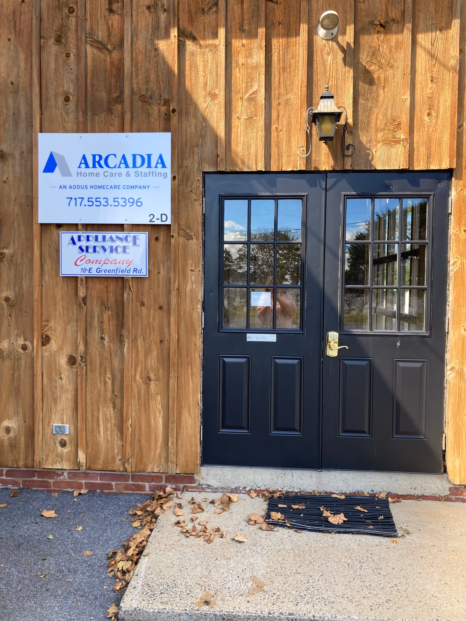 Wood-clad exterior with black double doors and Arcadia Home Care sign at the entrance.
