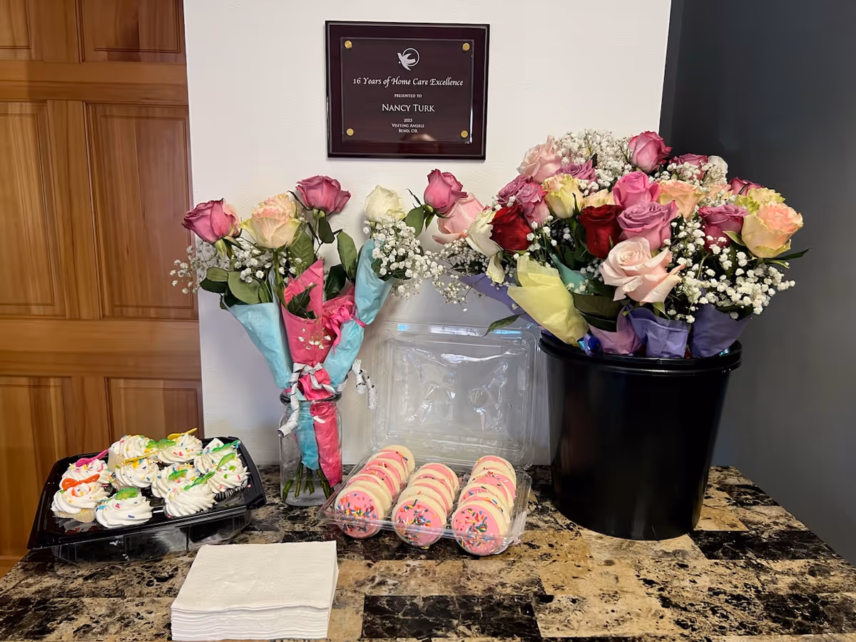 Bouquets of roses and flowers with cupcakes on a marble counter, plaque on wall.