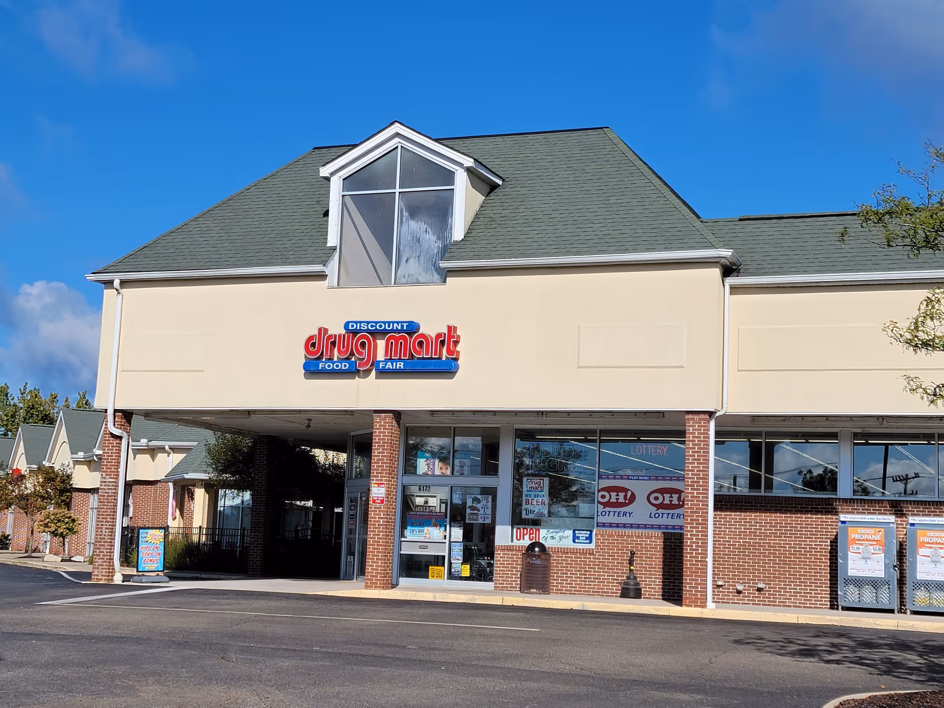 Exterior view of Discount Drug Mart storefront with beige facade and brick columns.