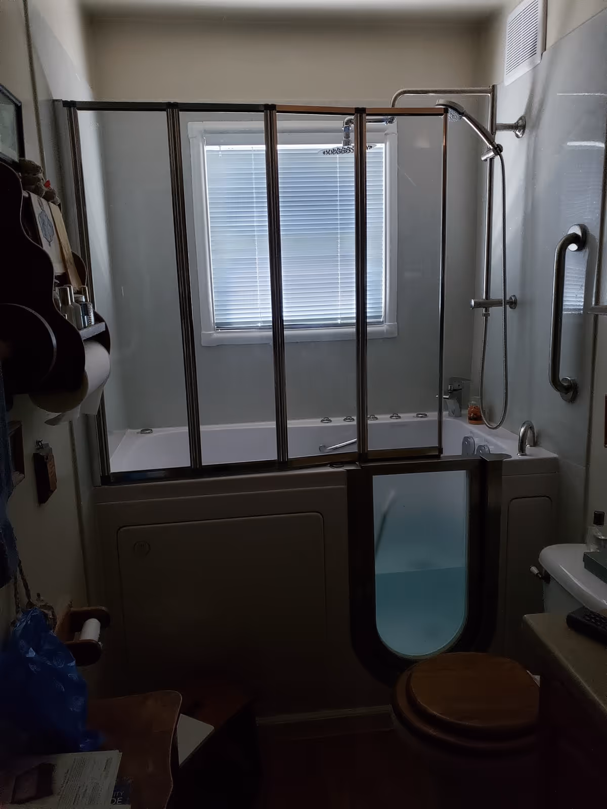 Bathroom with walk-in tub and glass doors, grab bars, and a window.