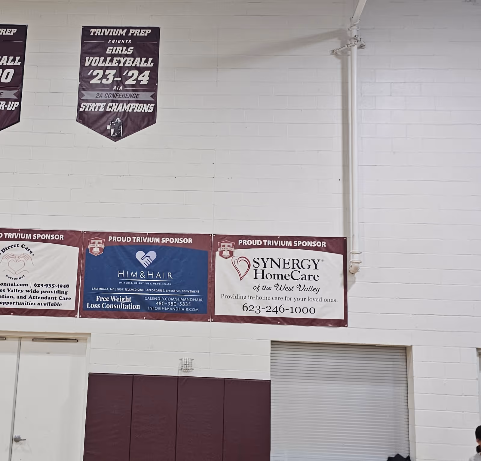 Indoor wall with sponsor banners, including Synergy HomeCare advertisement.