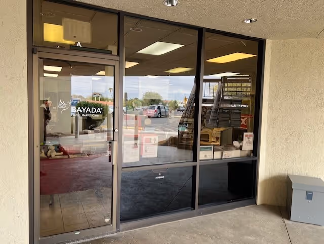 Glass entrance doors at BAYADA Assistive Care, showing interior shelves and staircase.
