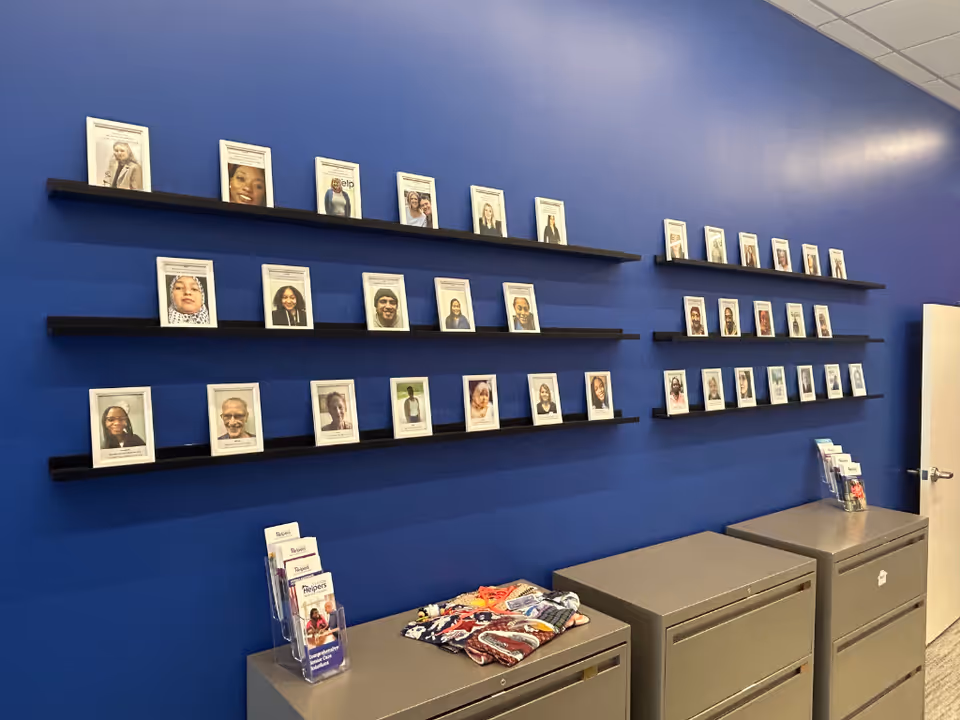 Blue wall with framed portraits on black shelves above gray filing cabinets.