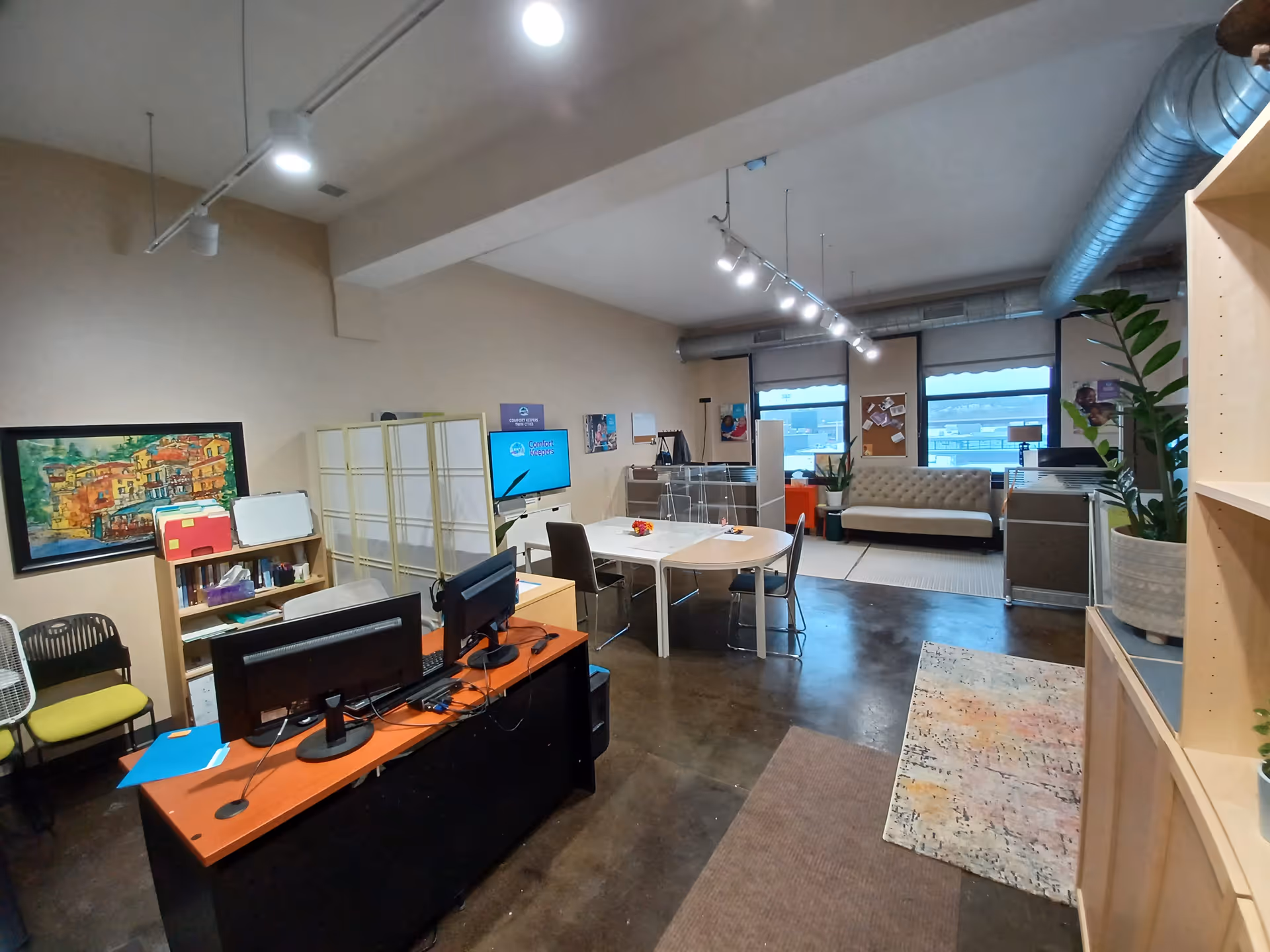 Office-like facility interior with desks, computers, a conference table, and a lounge area.