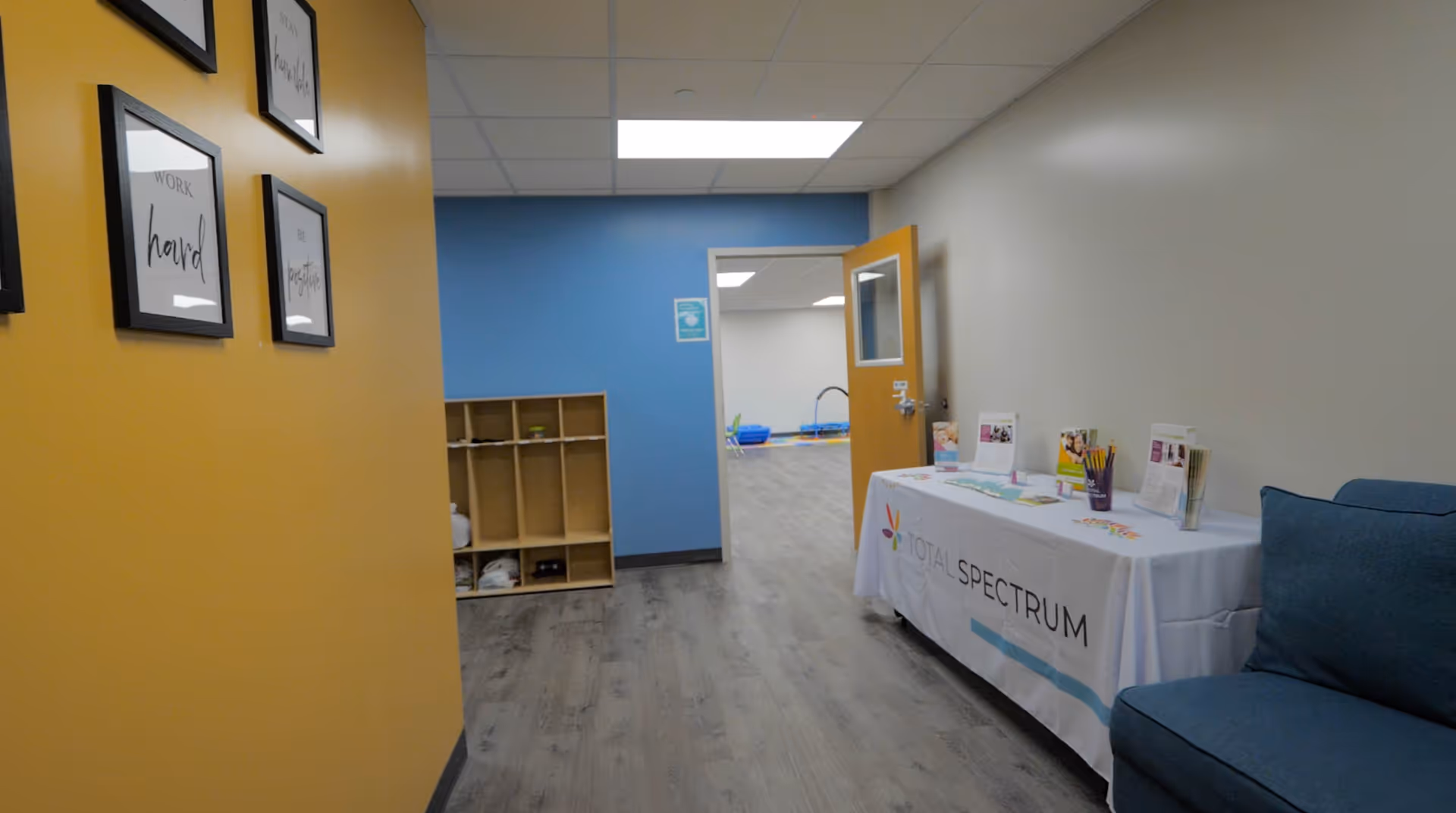 Interior hallway with yellow wall, cubbies, blue accent wall, and Total Spectrum information table.