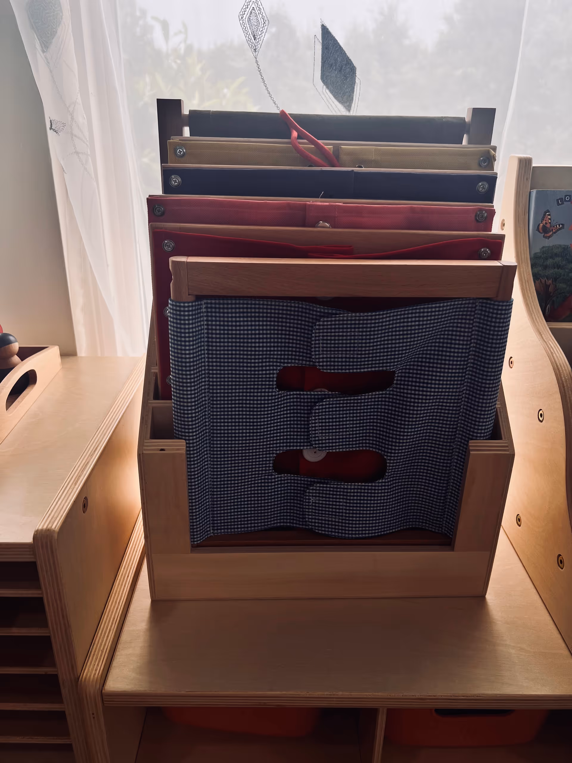 Wooden desk with tiered file organizers holding colorful folders and a blue checkered fabric cover