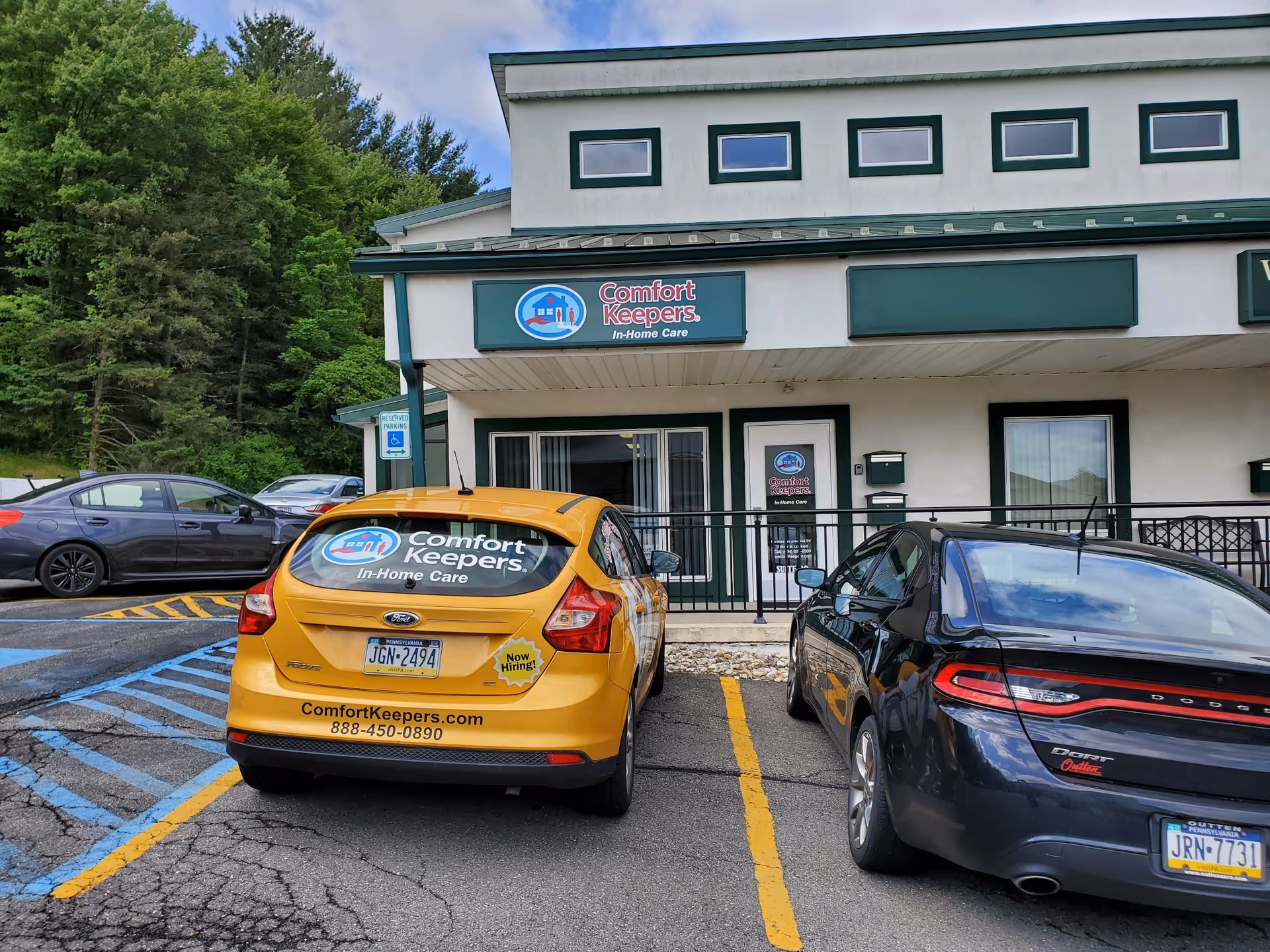Exterior view of Comfort Keepers building with parked cars in front.