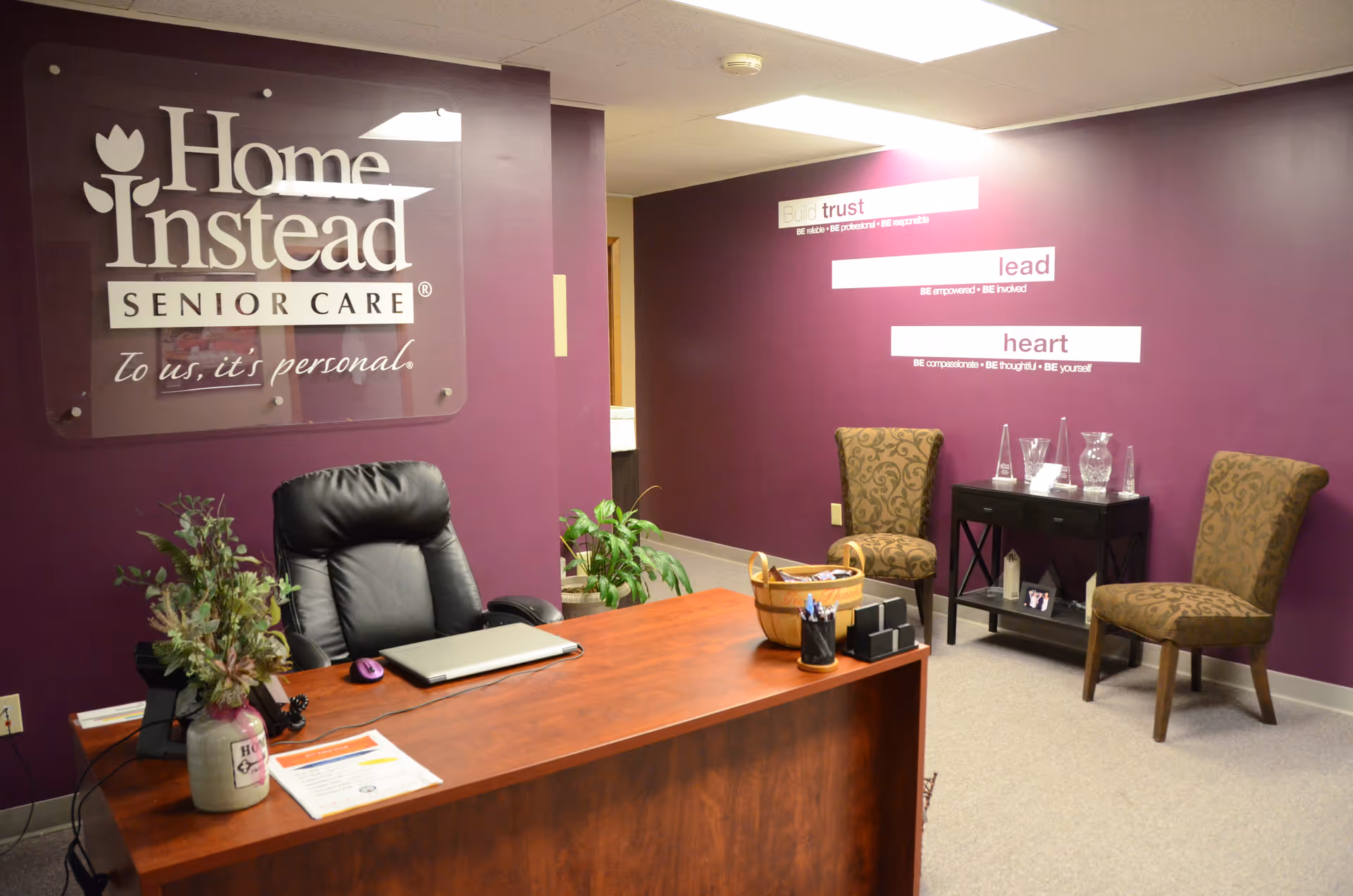 Reception desk in a purple Home Instead senior care lobby with chairs.