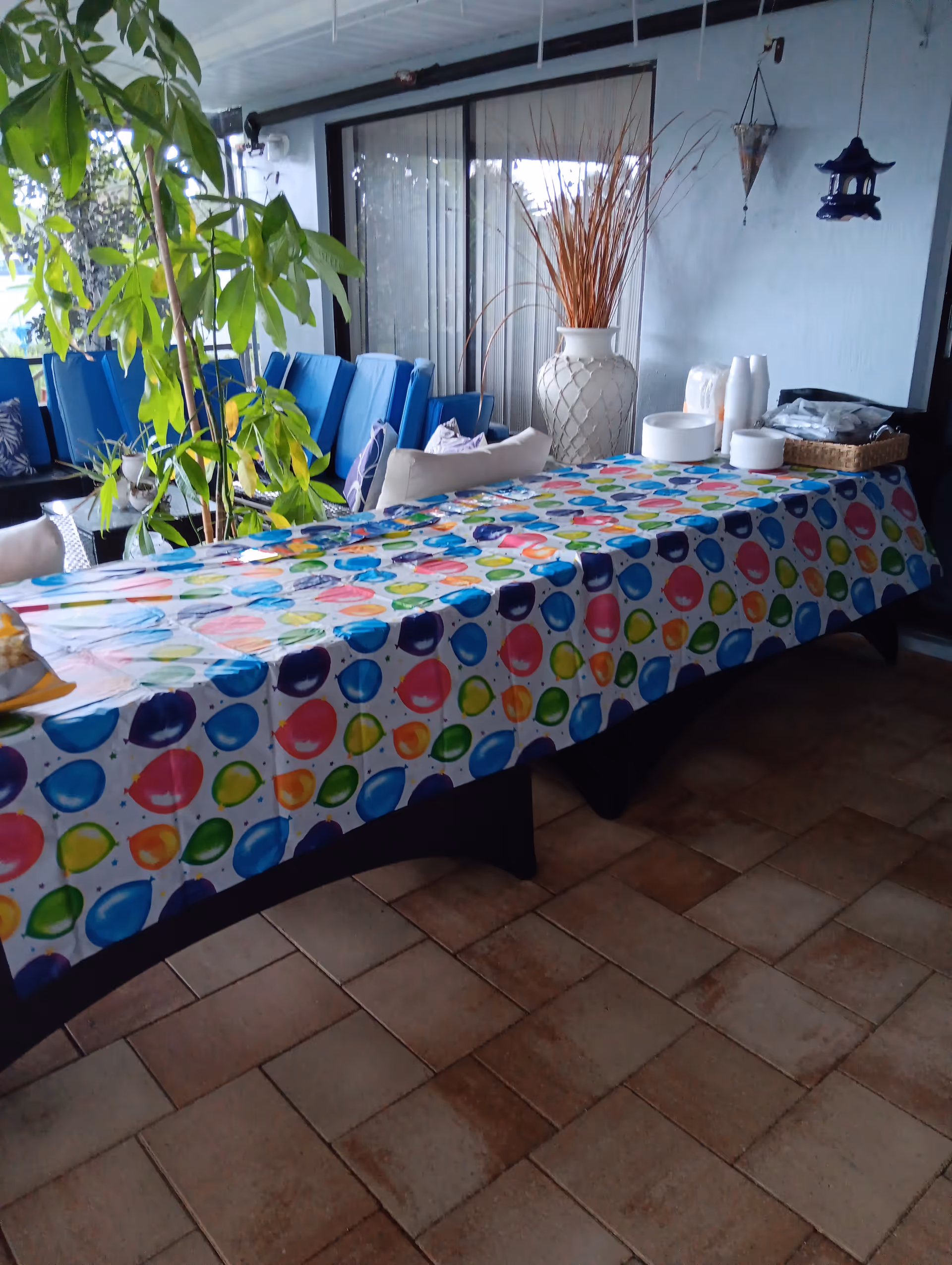 Outdoor patio with a long table covered in a colorful balloon-pattern tablecloth and chairs.