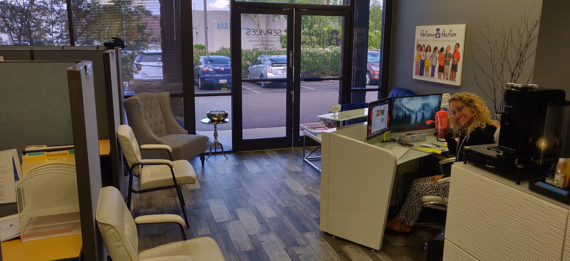 Reception area featuring a smiling staff member at a computer and waiting chairs.
