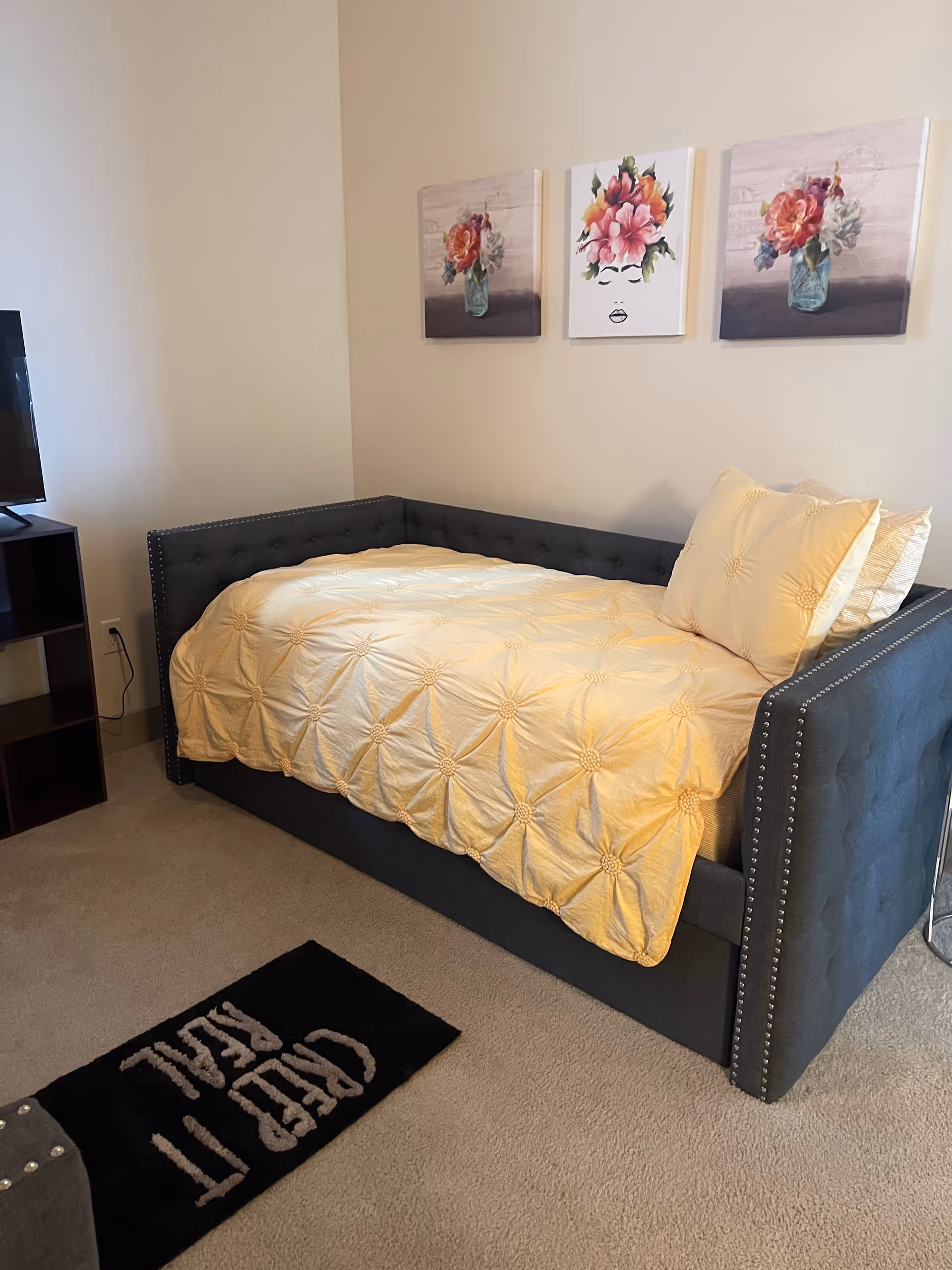 Cozy bedroom at Nesta's Wellness Retreat with tufted gray bed and floral wall art.