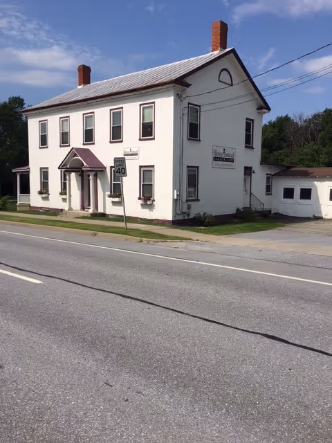 White two-story building on a street with a Home Instead sign.