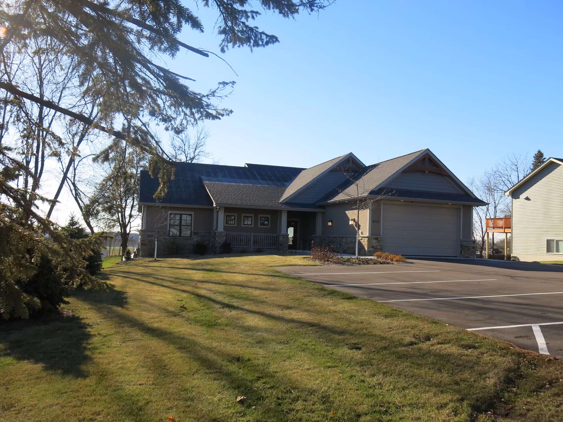 Front exterior view of a single-story senior living facility with parking and lawn.