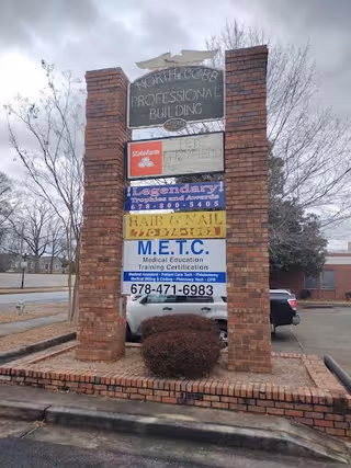 Brick sign tower with multiple business signs at the front of a building complex.